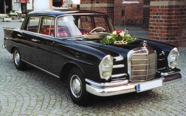 Hochzeit verzierter Oldtimer Mercedes 220 SE vor Rathaus